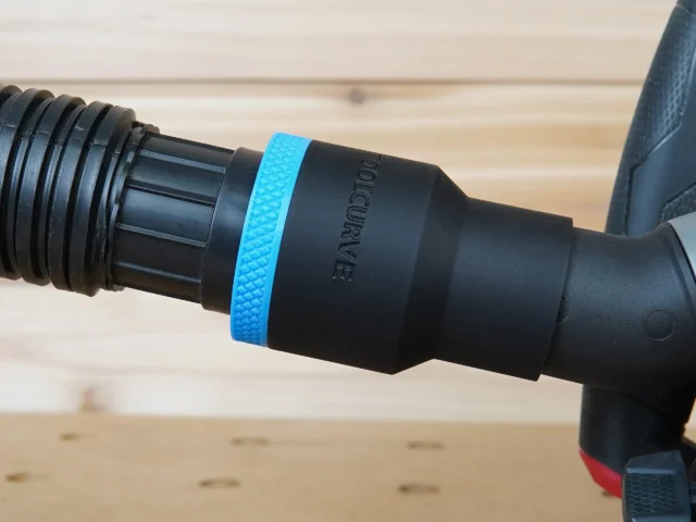 Black ToolCurve 1-7/8 inch hose adapter with blue grip ring joining a vacuum hose to a Milwaukee track saw port