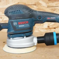 Black ToolCurve 1-7/8 inch hose adapter with blue band joining a vacuum hose to a Bosch ROS65VC sander dust port