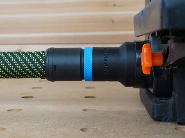 Black hose adapter with blue band and orange quick-release collar attached to green-and-yellow braided hose on Wen belt and disc sander