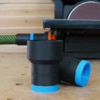 Two black ToolCurve hose adapters with blue textured ends standing on a bench beside a Wen belt and disc sander