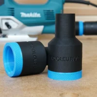 Black and blue plastic hose adapter with "ToolCurve" and "Makita" text molded into the body, shown alongside its blue threaded ring component on a wooden surface with a Makita jig saw blurred in the background
