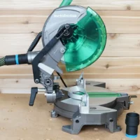 ToolCurve hose adapter installed on a Metabo HPT miter saw dust port, with a green dust collection hose connected