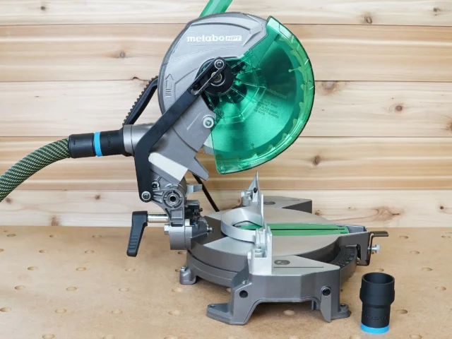 ToolCurve hose adapter installed on a Metabo HPT miter saw dust port, with a green dust collection hose connected