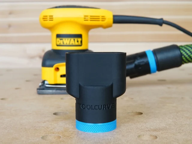 Black ToolCurve hose adapter with blue band, shown in front of a DeWalt 1/4 sheet palm sander