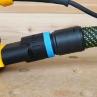 Black hose adapter with blue band attached to Dewalt palm sander dust port, connected to green braided hose