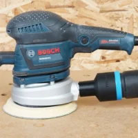 Black 36mm hose adapter with blue band joining an extractor hose to a Bosch ROS65VC sander dust port