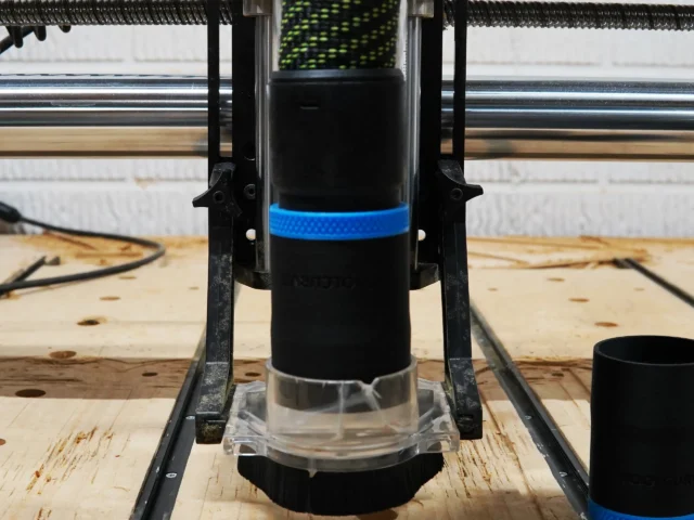 Black 36mm hose adapter with blue band installed on an Onefinity CNC Suck It Dust Boot Pro over a spoilboard
