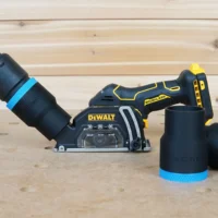 Black 36mm ToolCurve hose adapter with blue band joining a vacuum hose to a DeWalt cut-out tool dust port, two spare adapters beside it