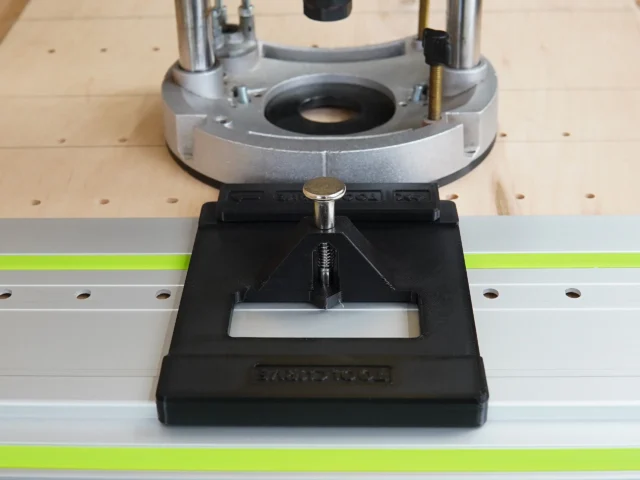 Black LR 32 adapter plate with brass knob mounted on Festool guide rail below Dewalt 625 router base