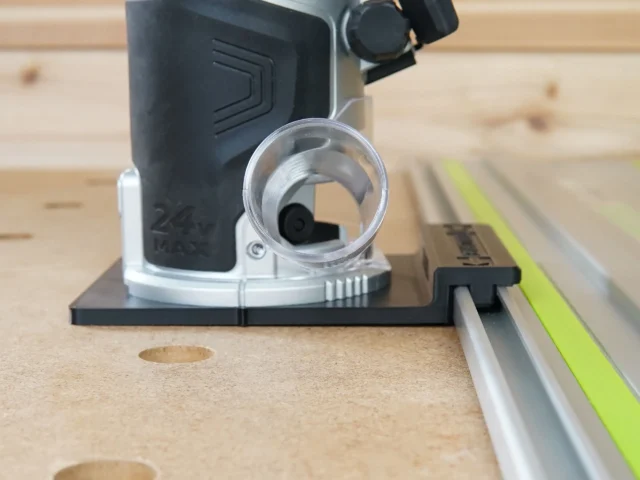 Kobalt 24v router guide rail adapter mounted on a router, attached to a Festool guide rail on wooden workbench