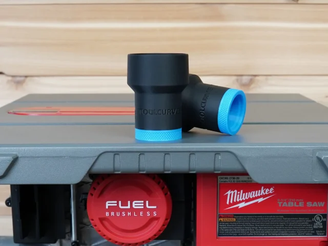 Black ToolCurve hose adapter with blue grip ring, mounted on Milwaukee M18 table saw dust port