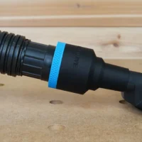 Black 1-7/8 inch ToolCurve hose adapter with blue ring joining a vacuum hose to a yellow Dewalt disc sander