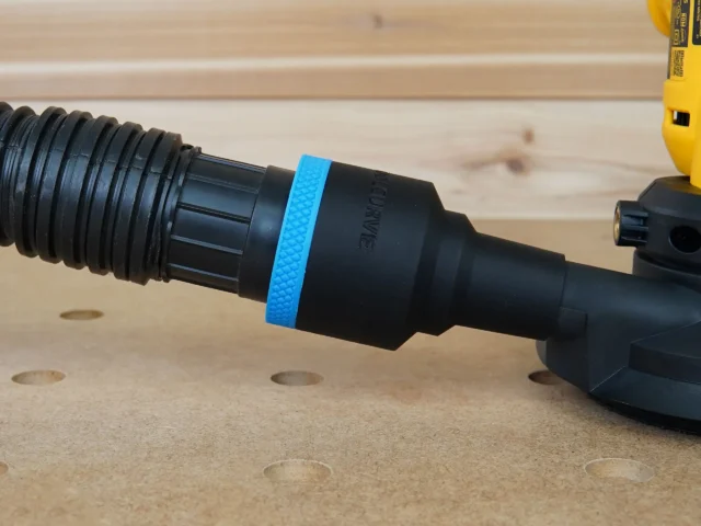Black 1-7/8 inch ToolCurve hose adapter with blue ring joining a vacuum hose to a yellow Dewalt disc sander