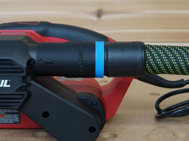 ToolCurve hose adapter attached to SKIL belt sander, with blue band and green braided hose connected