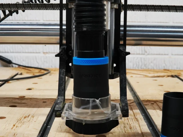 Black 1-7/8 inch hose adapter with blue grip ring installed on an Onefinity CNC Suck It dust boot