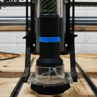 Hose adapter mounted on Onefinity CNC dust boot, showing clear base and black body with blue band, attached to workshop track saw