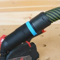 Black hose adapter with blue grip band attached to Milwaukee 12v cut out tool with green and black hose connected