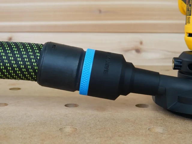 Black ToolCurve 36mm hose adapter with blue ring joining a green vacuum hose to a DeWalt disc sander dust port