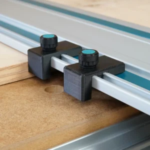 Two black drop stops with teal-capped knurled knobs clamped to a Makita guide rail against a plywood edge
