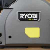 ToolCurve track saw dust cover with yellow snap-on panel attached to Ryobi One+ HP track saw