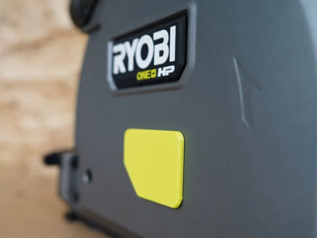 Yellow snap-on dust cover attached to Ryobi ONE+ HP track saw, showing low-profile design and branded nameplate
