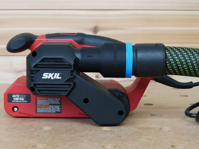 Black ToolCurve 36mm hose adapter with blue ring fitted to the dust port of a red SKIL belt sander