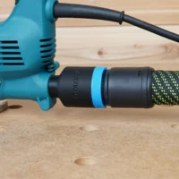Black hose adapter with blue band attached to turquoise Makita jig saw, connected to green and black braided hose