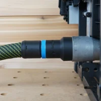 Black hose adapter with blue band attached to green-and-black dust extraction hose, connected to Milwaukee M18 Table Saw port