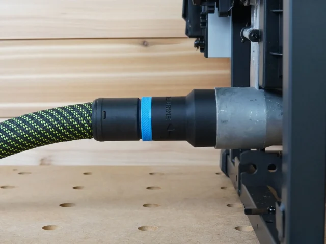 Black hose adapter with blue band attached to green-and-black dust extraction hose, connected to Milwaukee M18 Table Saw port