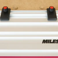 Two black limit stops with red knobs mounted on a Milescraft guide rail, spaced apart for repeatable cuts
