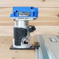 Kobalt 24v compact router on a black guide rail adapter base riding a Makita track on an MDF bench
