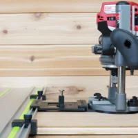 Milwaukee M18 2 1/4" HP router mounted on LR 32 plunge base with rail adapter, positioned over a Festool-style track with guide stops for hole drilling