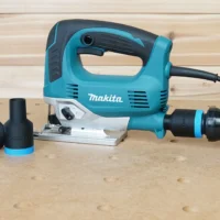 Black ToolCurve 1-1/4" hose adapter with blue ring attached to a Makita jig saw dust port, spare adapter alongside