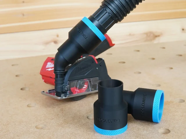 Black 1-7/8" hose adapter with blue trim installed on a Milwaukee 12v cut-out tool, second adapter lying alongside