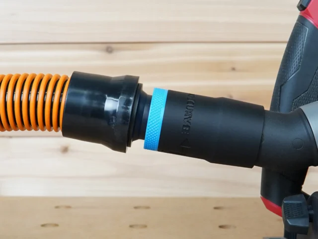 Black 1-1/4 inch hose adapter with blue grip ring joining an orange hose to a Milwaukee track saw port