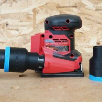 Black 1-7/8 inch ToolCurve hose adapter with blue band connected to a Milwaukee sheet sander, second adapter beside it