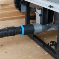 Black ToolCurve 1-7/8" hose adapter with blue ring joining a vacuum hose to the Milwaukee M18 table saw dust port