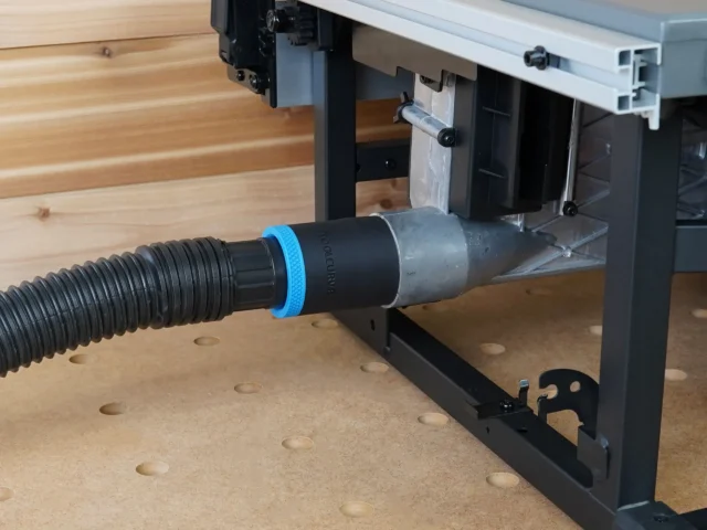 Black ToolCurve 1-7/8" hose adapter with blue ring joining a vacuum hose to the Milwaukee M18 table saw dust port