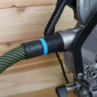 Black hose adapter with blue band attached to Metabo HPT miter saw dust port, connected to green and yellow braided hose