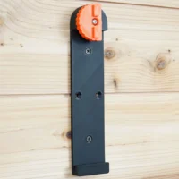 Dark gray wall mount for Wen track saw rails with orange locking head at top, three mounting holes visible along length