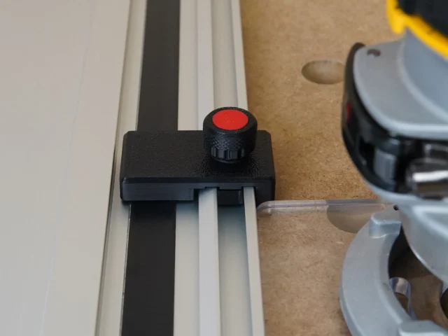 Black plastic limit stop with red knurled knob mounted on Milwaukee track saw guide rail