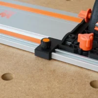 Black limit stop with orange knurled knob mounted on Wen guide rail, shown on workbench with orange rail clamps