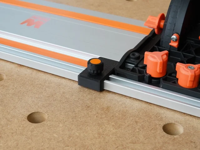 Black limit stop with orange knurled knob mounted on Wen guide rail, shown on workbench with orange rail clamps