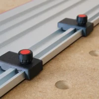 Two black limit stops with red knobs mounted on aluminum guide rails, positioned at different points along the track