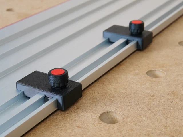 Two black limit stops with red knobs mounted on aluminum guide rails, positioned at different points along the track