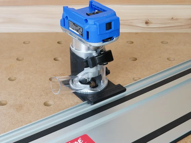 Kobalt 24v router attached to aluminum guide rail on perforated workbench, showing black mounting bracket and clear base detail