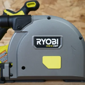 Yellow snap-on arbor dust cover installed on the gray blade housing of a Ryobi ONE+ HP track saw, side view