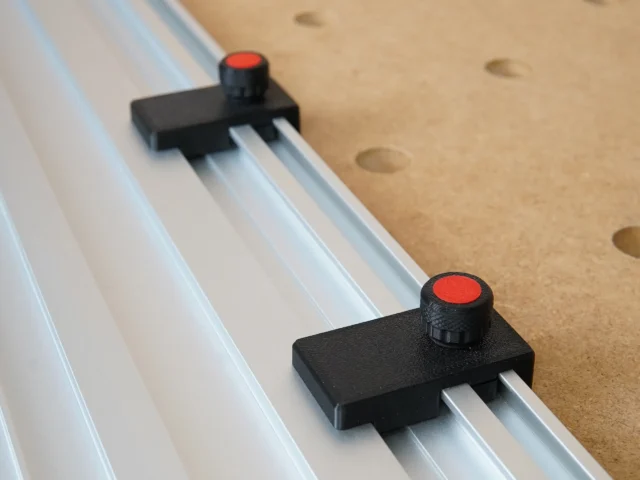 Two black limit stops with red knobs mounted on parallel aluminum track rails