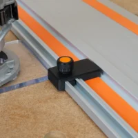 Black limit stop with orange knurled knob mounted on a Wen track saw guide rail
