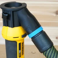 Black hose adapter attached to yellow Dewalt drywall cut out tool, with blue tape and green-patterned hose connected below